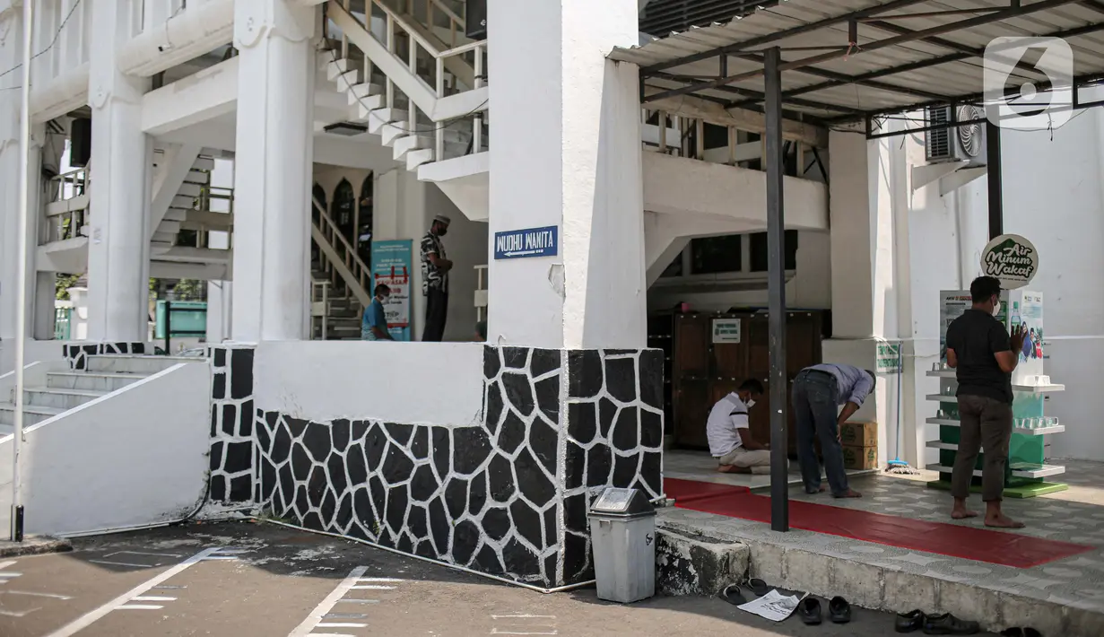 Sejumlah warga melaksanakan salat zuhur di halaman depan Masjid Cut Meutia, Jakarta, Jumat (18/9/2020). Pemprov DKI Jakarta kembali meniadakan kegiatan ibadah salat Jumat dan salat lima waktu berjemaah di semua Masjid Raya selama PSBB. (Liputan6.com/Faizal Fanani)