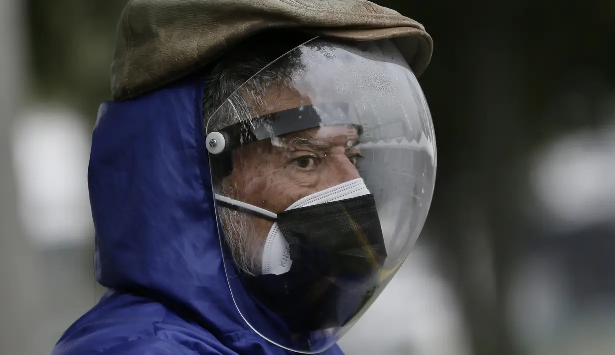 Seorang pria yang mengenakan pelindung wajah penuh dan masker ganda  menunggu gilirannya divaksinasi Covid-19 di luar pusat vaksinasi Social Security Institute di Quito, Ekuador, Kamis (6/5/2021). Para lansia dan pendampingnya menunggu berjam-jam untuk divaksinasi. (AP Photo/Dolores Ochoa)