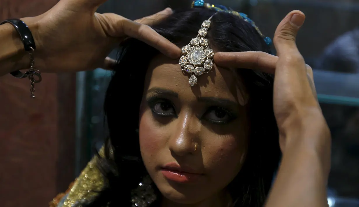 Seorang model sedang di rias dibelakang panggung saat mengikuti lomba rias pengantin lokal di Karachi, Pakistan, 22 Maret 2016.Sejumlah wanita mengikuti lomba yang diadakan di sebuah pusat pembelajaan. (REUTERS / Akhtar Soomro)