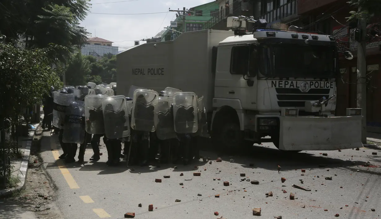 Polisi Nepal berlindung dari serangan batu saat bentrok dengan warga ketika kegiatan menarik kereta Dewa Rato Machhindranath dalam sebuah festival keagamaan di Lalitpur, Nepal (3/9/2020). Kereta Dewa Rato Machhindranath biasanya ditarik berkeliling kota selama sebulan.  (AP Photo/Niranjan Shrestha)