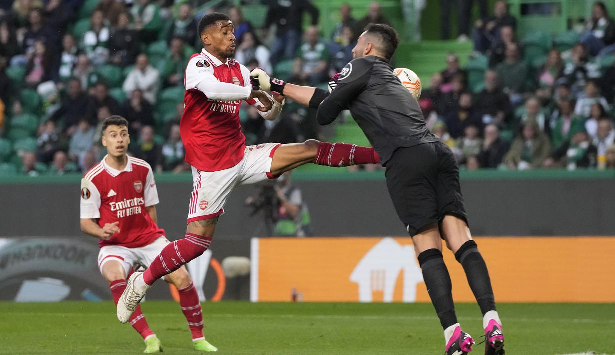<p>Pemain Arsenal, Reiss Nelosn (kiri) berebut bola dengan kiper Sporting CP, Antonio Adan pada laga leg pertama Liga Europa 2022/2023 di Jose Alvalade Stadium, Lisbon, Jumat (10/03/2023) dini hari WIB. Laga berakhir dengan skor imbang 2-2. (AP Photo/Armando Franca)</p>
