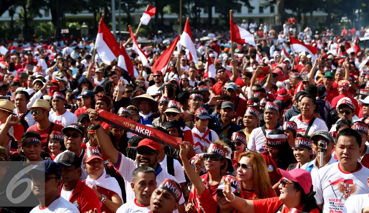 Sejumlah peserta menggunakan ikat kepala yang bertuliskan Stand of NKRI dan membawa bendera merah putih saat mengikuti aksi Parade Bhineka Tunggal Ika di kawasan Patung Kuda, Jalan MH Thamrin, Jakarta Pusat, Sabtu (19/11). (Liputan6.com/Gempur M. Surya)
