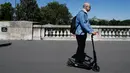 Seorang pria menggunakan skuter listrik saat beraktivitas di Paris, Prancis (9/7). Skuter listrik ini dibuat oleh perusahaan AS Lime yang merupakan penyewaan transportasi sepeda dan skuter di berbagai kota. (AFP Photo/Francois Guillot)