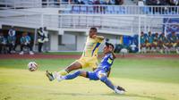 Bek kiri Arema FC, Johan Alfarizi menjuauhkan bola dari kejaran striker Persib Bandung, Uilliam Barros dalam laga pekan keenam BRI Super League 2025/2026 di Stadion Kanjuruhan, Kabupaten Malang, Senin (22/9/2025). (Bola.com/Iwan Setiawan).