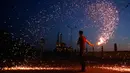 Seorang pemuda Palestina mengayunkan kembang api di depan sebuah masjid di Kota Gaza, Palestina (16/5). Mereka bermain kembang api untuk menyambut puasa pertama di bulan Ramadan. (AFP Photo/Mohammed Abed)