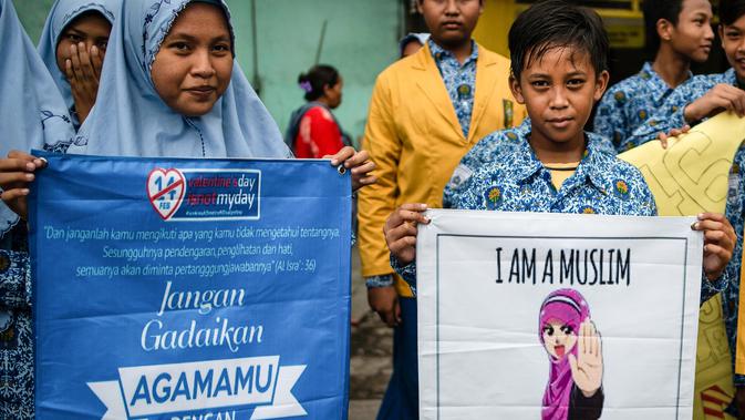 Dua orang pelajar menunjukkan spanduk saat menggelar demonstrasi menolak perayaan Hari Valentine di Surabaya, Jawa Timur, Kamis (14/2). Pelajar menilai Valentine sebagai pengaruh budaya asing. (Juni Kriswanto/AFP)