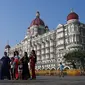 Turis berkunjung di dekat hotel Taj Mahal Palace, salah satu lokasi serangan teroris 2008, di Mumbai (26/11/2021). (AFP/Punit Paranjpe)