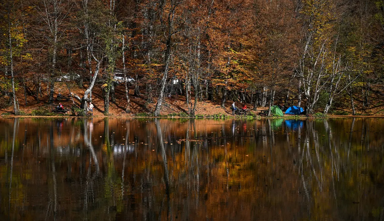 Orang-orang menikmati hari musim gugur yang cerah di Taman Nasional Yedigoller di distrik Bolu, Turki pada 9 November 2021. Taman Nasional Yedigoller mengundang banyak pecinta alam untuk berkemah, ataupun sekedar menikmati ketenangan. (Ozan KOSE / AFP)