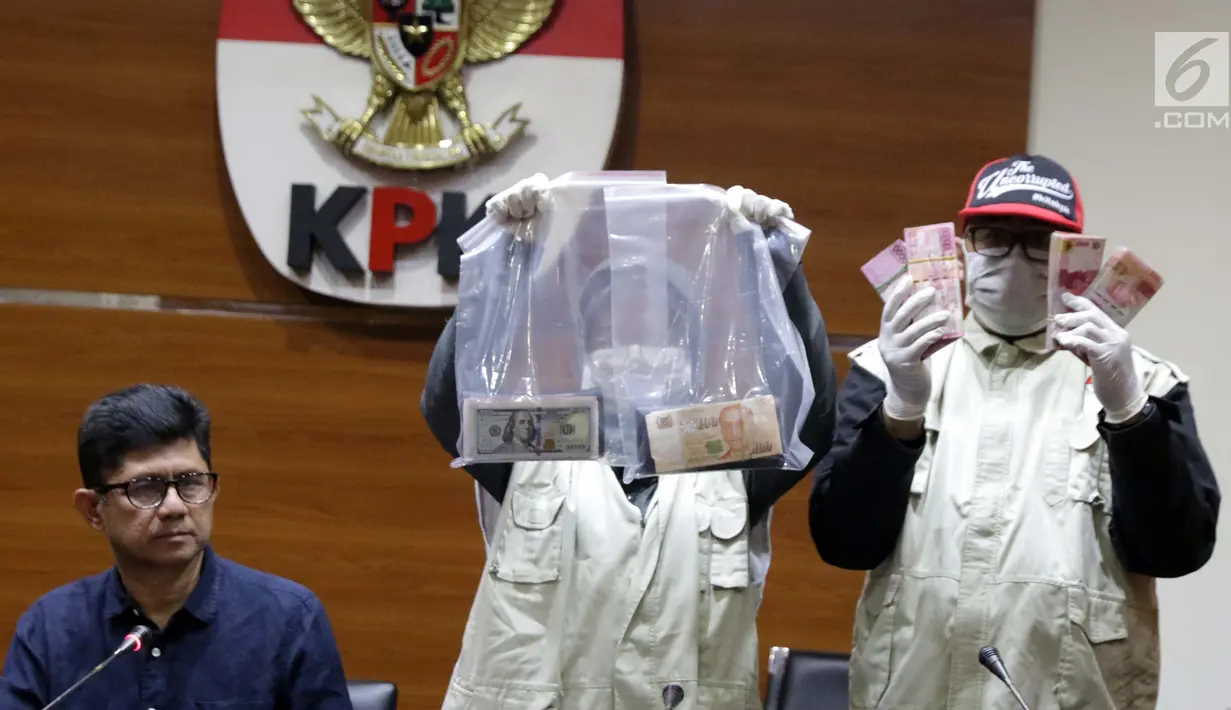 Petugas KPK melihat barang bukti uang hasil OTT di Gedung KPK, Jakarta, Sabtu (26/6/2019). Dalam OTT tersebut, KPK menyita uang 20.874 dolar Singapura, 700 USD dan Rp 200 juta dari lima tersangka. (Liputan6.com/Helmi Fithriansyah)