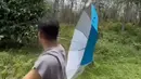 Tak berhenti sampai di situ, Jirayut terlihat berdiri santai sambil memegang payung di bawah terik matahari. Latar belakangnya tetap kebun karet yang rindang dan hijau, menambah kesan sejuk di tengah cuaca panas. Ia menceritakan bahwa luas kebun karetnya hampir mencapai satu hektar.(Liputan6.com/IG/@jirayutdaa4official)