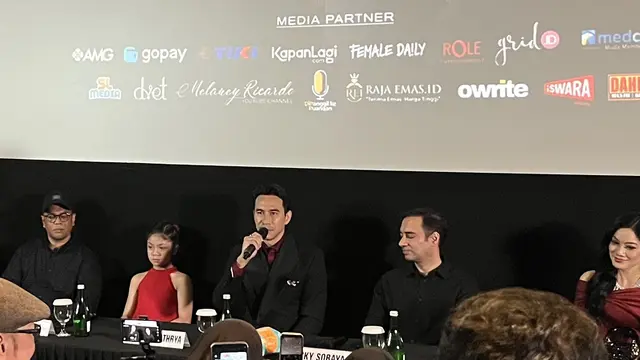 Darius Sinathrya, memegang mic dalam konferensi pers dan screening film "The Doll Ghawiah" di kawasan Jakarta pada (16/10/2026)/ (Liputan6.com/Afradhiya N. R)