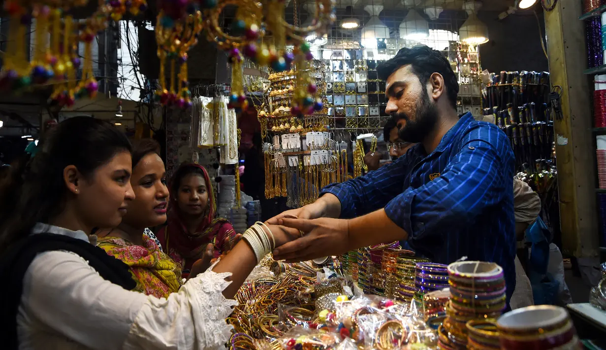 Seorang wanita Pakistan mencoba gelang di pasar menjelang Hari Raya Idul Fitri di Karachi (3/6/2019). Umat Muslim di seluruh dunia sedang bersiap untuk merayakan Hari Raya Idul Fitri, yang menandai akhir bulan puasa Ramadan. (AFP Photo/Asif Hassan)