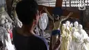Perajin membawa patung rohani yang telah selesai di Serpong, Tangerang Selatan, Banten, Kamis (17/12/2020). Pemesanan patung rohani berbahan dasar fiber resin meningkat dua kali lipat dari hari biasa mendekati Hari Raya Natal. (Liputan6.com/Angga Yuniar)