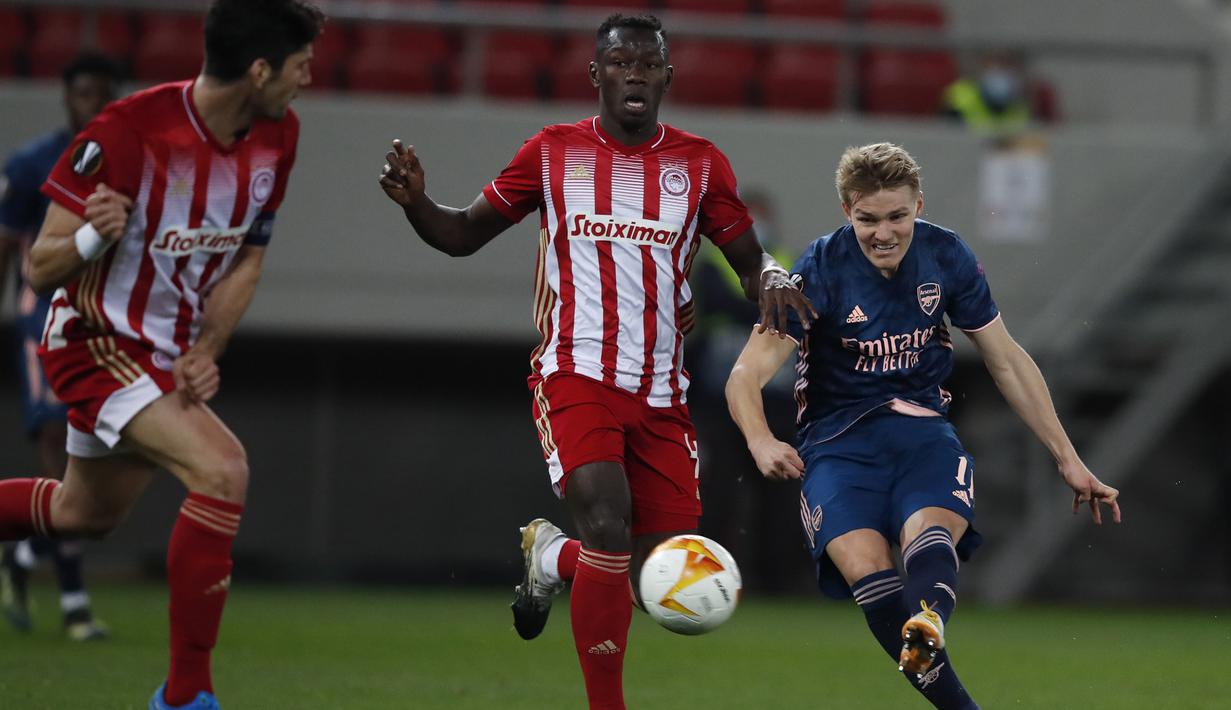 Striker Arsenal, Martin Odegaard (kanan) melepaskan tendangan yang berbuah gol pertama timnya ke gawang Olympiakos dalam laga leg pertama babak 16 besar Liga Europa 2020/2021 di Georgios Karaiskakis Stadium, Kamis (11/3/2021). Arsenal menang 3-1 atas Olympiakos. (AP/Thanassis Stavrakis)