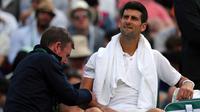 Petenis Serbia, Novak Djokovic mendapat perawatan medis saat melawan petenis Ceko, Tomas Berdych pada babak perempatfinal Wimbledon 2017, Rabu (12/7). Juara Wimbledon tiga kali itu gagal melanjutkan laga lantara cedera. (Gareth Fuller/PA via AP)
