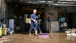 Penduduk membersihkan lumpur dari sebuah rumah setelah banjir surut di distrik Shibata, Prefektur Miyagi, Minggu (13/10/2019). Topan dahsyat Hagibis yang menerjang sejumlah wilayah di Jepang menyebabkan banjir di beberapa lokasi. (Photo by CHARLY TRIBALLEAU/ AFP)