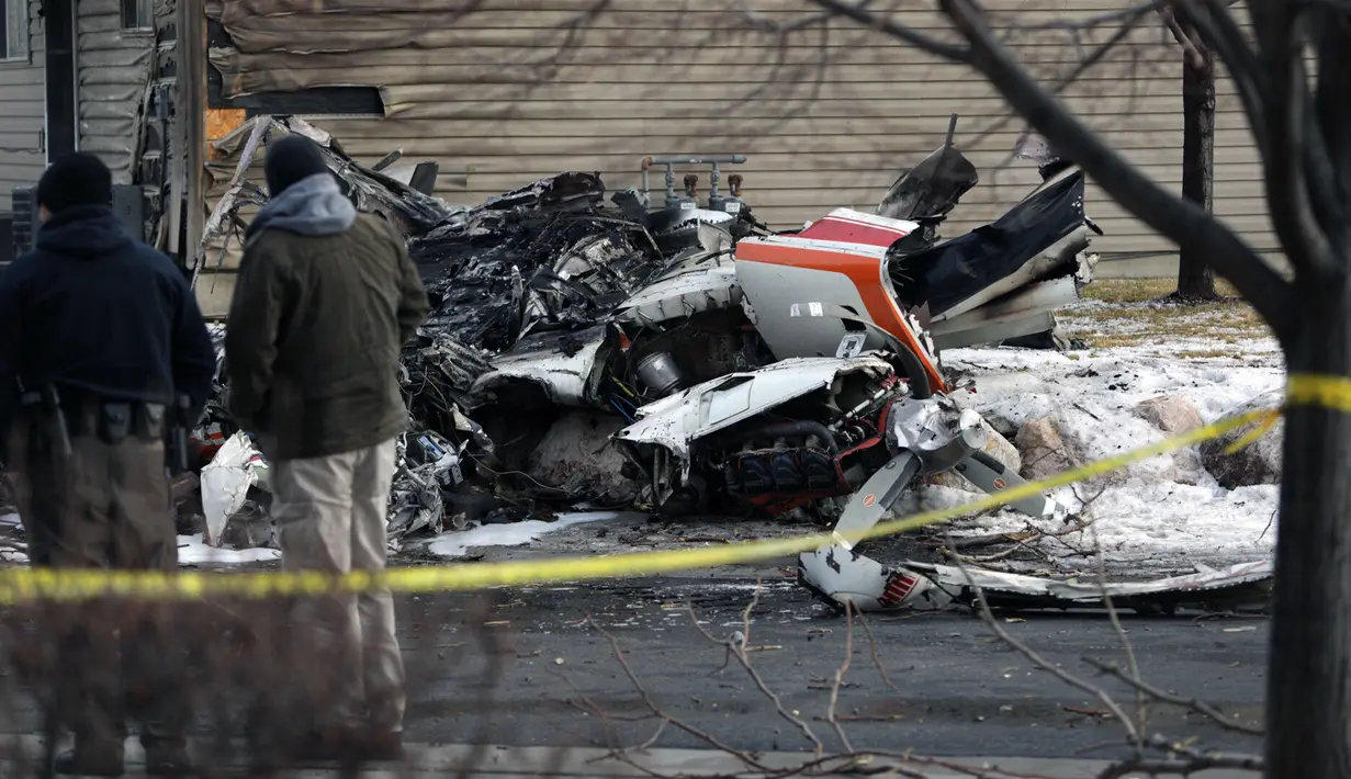 Warga melihat puing-puing pesawat pribadi yang jatuh di kawasan perumahan Roy, Utah, Amerika Serikat, Rabu (15/1/2020). Seorang pilot berusia 64 tahun dilaporkan tewas. (Ben Dorger/Standard-Examiner, via AP)