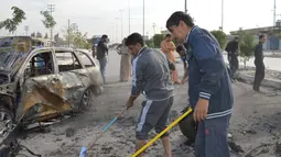 Warga membersihkan puing usai terjadi ledakan di Ameriyat Falluja, Irak, Jumat (18/11). Serangan yang diduga dilakukan ISIS ini sedikitnya menewaskan 17 orang dan belasan lainnya luka-luka. (Reuters/Osamah Waheeb) 