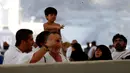 Jemaah haji melempar jumrah sambil menggendong anak sebagai simbol mengusir setan saat ibadah haji di Mina, Arab Saudi (12/09). (REUTERS/Ahmed Jadallah)