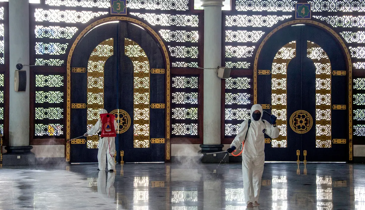 Pekerja dari otoritas penanggulangan bencana setempat menyemprotkan desinfektan di sebuah masjid di Surabaya, Jawa Timur, Selasa (17/3/2020). Kegiatan tersebut dilakukan untuk mencegah penyebaran Virus Corona COVID-19. (Photo by Juni Kriswanto / AFP)