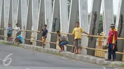 Sejumlah bocah menunggu pengendara yang melintas untuk melempar uang koin di Jembatan Cikalong, Jawa Barat, Sabtu (2/7). Memasuki mudik Lebaran, jumlah pencari uang sedekah di kawasan itu meningkat dibanding hari biasa. (Liputan6.com/Gempur M Surya)