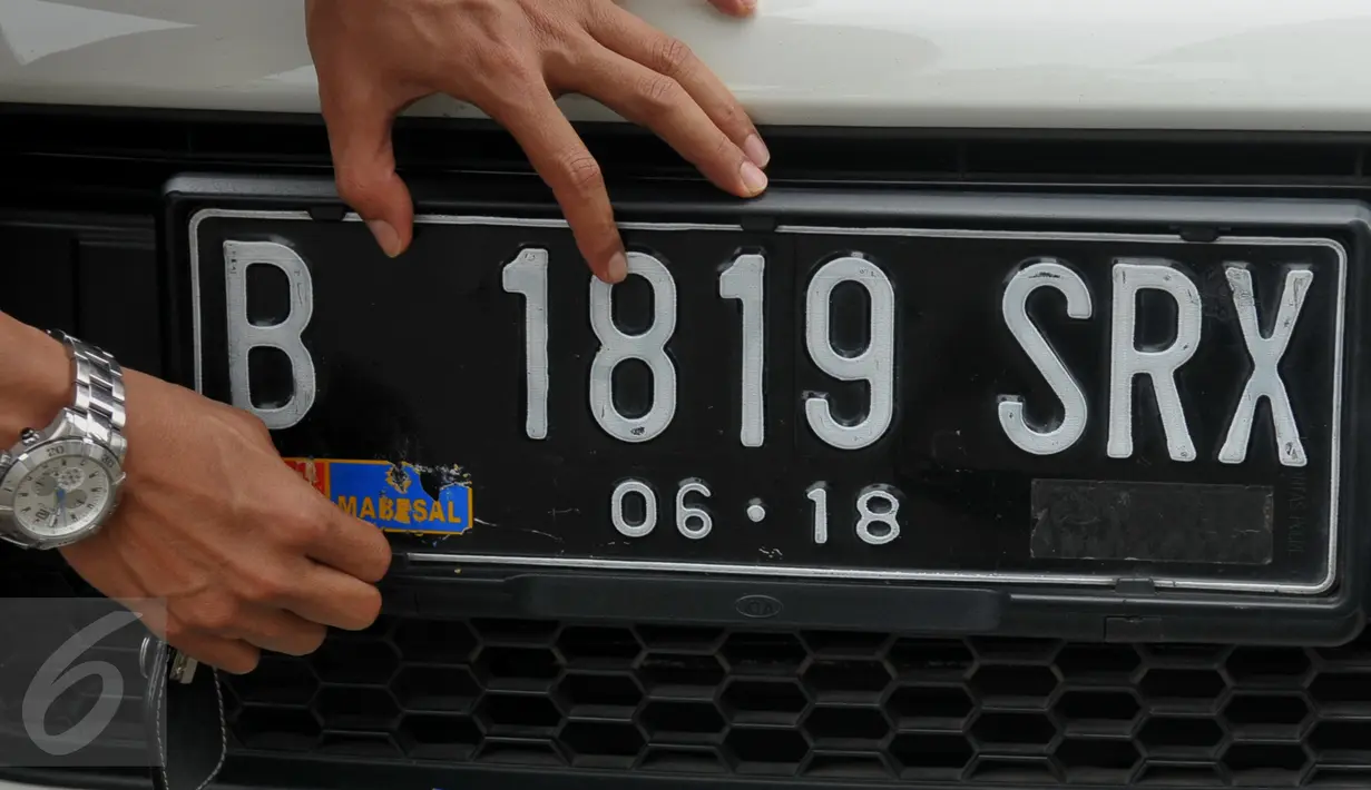 Pengendara mencopot stiker Mabes AL di plat mobil yang dikendarainya saat Operasi Gaktib Garnisun Tetap 1 di kawasan Pesing, Jakarta,  Kamis, (11/2/2016). (Liputan6.com/Faisal R Syam)