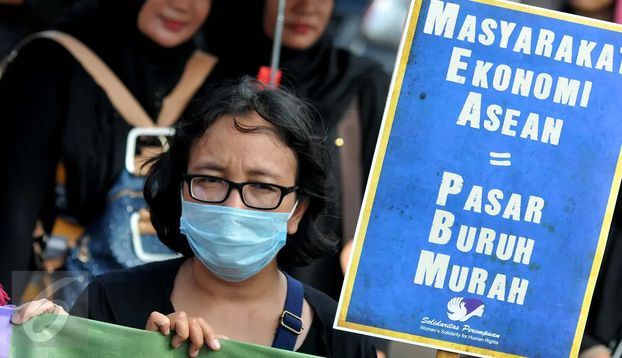 Seorang aktivis membawa tulisan saat melakukan aksi demo memperingati Hari Ibu di depan Istana Negara, Jakarta (22/12). Hal ini dilakukan dalam menyambut berlakunya Masyarakat Ekonomi ASEAN di Indonesia. (Liputan6.com/Gempur M Surya)