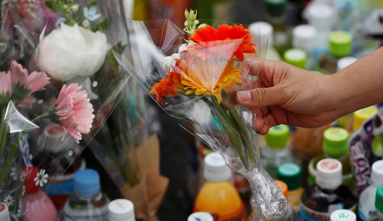 Seorang wanita manaruh bunga untuk untuk korban Penikaman Massal di Kawasaki, Jepang (29/5/2019). Kepolisian Jepang mengonfirmasi bahwa penikaman massal di kota tersebut menewaskan seorang anak perempuan berusia 11 tahun yang duduk di bangku SD dan pria berusia 39 tahun. (Reuters/Issei Kato)