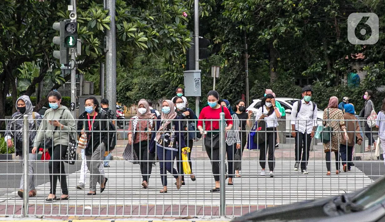 Orang-orang menyeberang jalan di kawasan Sudirman, Jakarta, Rabu (16/12/2020). Pemprov DKI bakal memberlakukan kebijakan WFH (work from home) bagi ASN sebesar 75 persen untuk mengantisipasi lonjakan kasus konfirmasi positif Covid-19 pada akhir tahun. (Liputan6.com/Faizal Fanani)