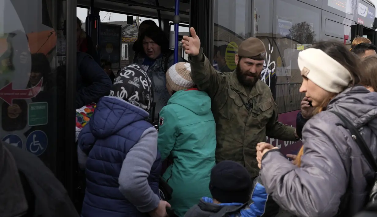 Tentara Polandia memberi arahan pada pengungsi Ukraina di perbatasan Medyka, Rabu (30/3/2022). Badan pengungsi PBB mengatakan lebih dari 4 juta orang telah meninggalkan Ukraina setelah invasi Rusia, tonggak baru dalam krisis pengungsi terbesar di Eropa sejak Dunia Perang II. (AP/Sergei Grits)