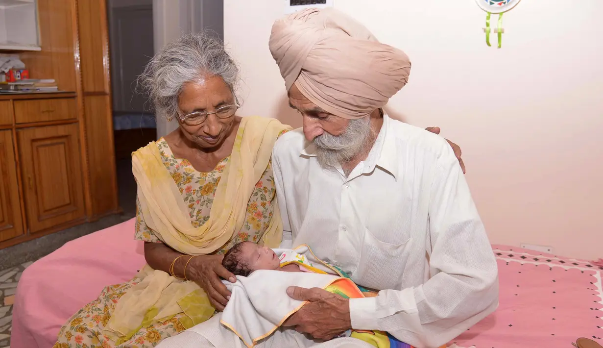 Daljinder Kaur (kiri) bersama sang suami Mohinder Singh Gill saat mengasuh anak mereka di Amritsar, India, Rabu (11/5). Bayi yang lahir bulan lalu ini dinamai Armaan.( NARINDER NANU / AFP)