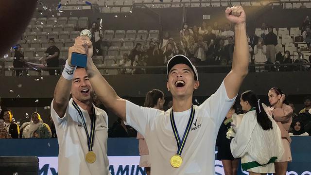 Raffi Ahmad dan Dion Wiyoko mengangkat piala kemenangan di acara Lagi-Lagi Tenis,