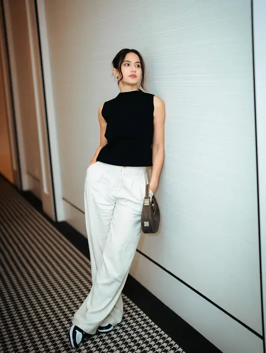 Gaya kasual super cantik dari Pevita Pearce pakai atasan hitam tanpa lengan dipadunya dengan celana panjang berwarna putih, sneakers dan tas tangan yang serasi. [Foto: Instagram/pevpearce]