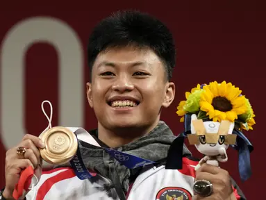 Lifter Indonesia Rahmat Erwin Abdullah merayakan di podium setelah memenangkan medali perunggu cabang angkat besi 73 kg putra Olimpiade Tokyo 2020 di Tokyo, Jepang, Rabu (28/7/2021). Rahmat Erwin Abdullah berhasil menyumbang medali perunggu untuk Indonesia. (AP Photo/Luca Bruno)