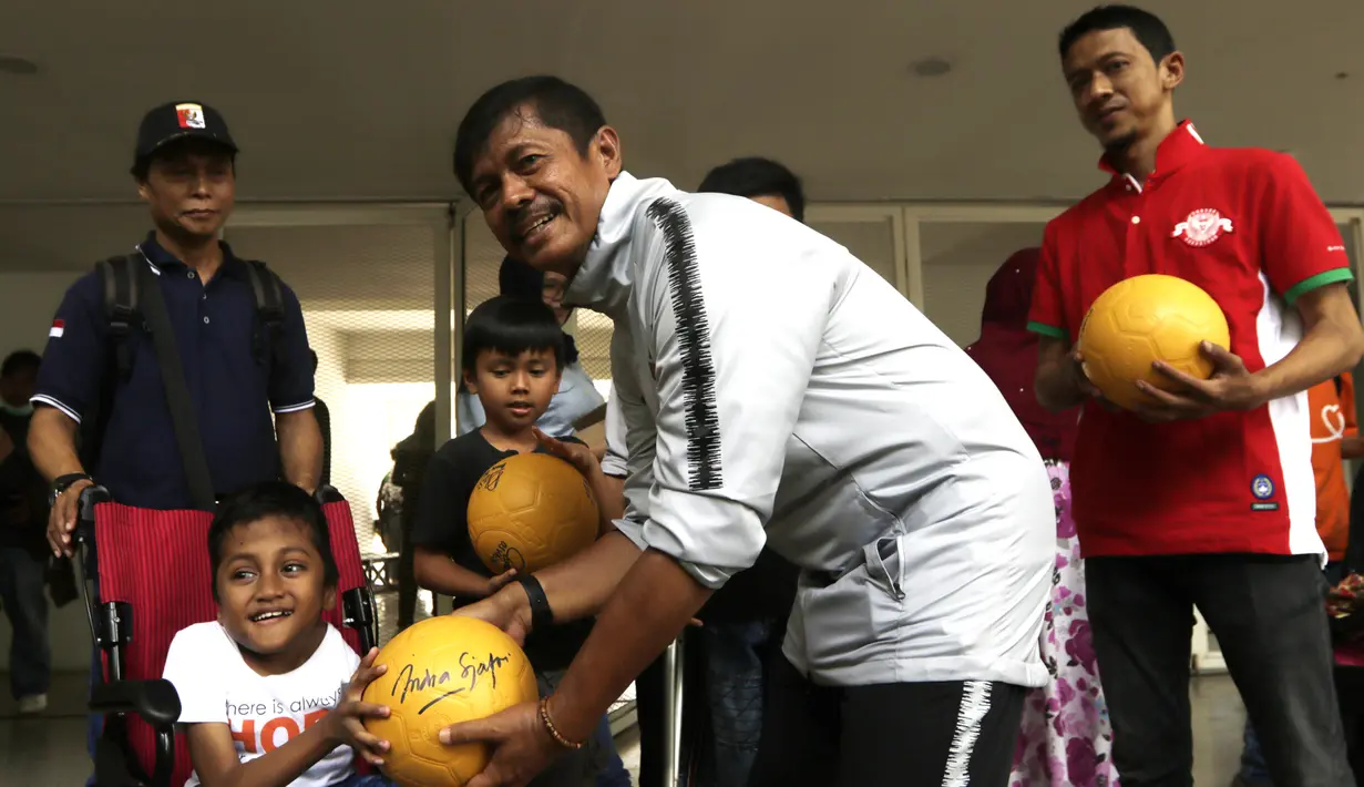 Pelatih Timnas Indonesia U-23, Indra Sjafri, memberikan bola kepada anak-anak yang datang ke Stadion Madya, Jakarta, Rabu (13/3). Sejumlah anak dari Yayasan Rumah Harapan Indonesia datang menemui Timnas U-23 (Bola.com/Vitalis Yogi Trisna)