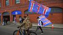 Para fans Glasgow Rangers dengan bersepeda dan berjalan kaki mengibarkan bendera klub di luar Ibrox Stadium (7/3/2021) untuk merayakan keberhasilan tim kesayangan mereka merebut gelar Liga Utama Skotlandia setelah memimpin 20 poin dari saingan terdekat, Glasgow Celtic. (AFP/Andy Buchanan)