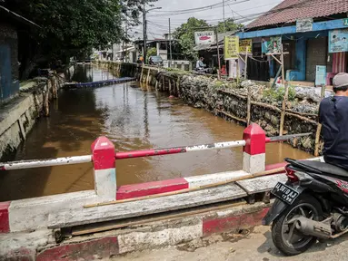 Pengendara motor melintas dekat bantaran Kali Induk Kramat Jati, Jakarta, Rabu(18/5/2022). Pemprov DKI Jakarta melalui Dinas Sumber Daya Air (SDA) berencana akan menormalisasi Kali Induk secara keseluruhan guna mencegah banjir yang melanda kawasan tersebut saat hujan deras mengguyur. (Liputan6.com/FaizaL Fanani)