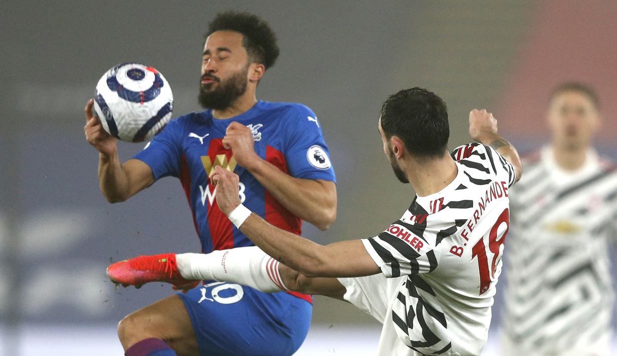 Gelandang Crystal Palace, Andros Townsend (kiri) berebut bola dengan gelandang Manchester United, Bruno Fernandes dalam laga lanjutan Liga Inggris 2020/21 pekan ke-27 di Selhurst Park, Rabu (3/3/202). Crystal Palace bermain imbang 0-0 dengan Manchester United. (AP/Adrian Dennis/Pool)