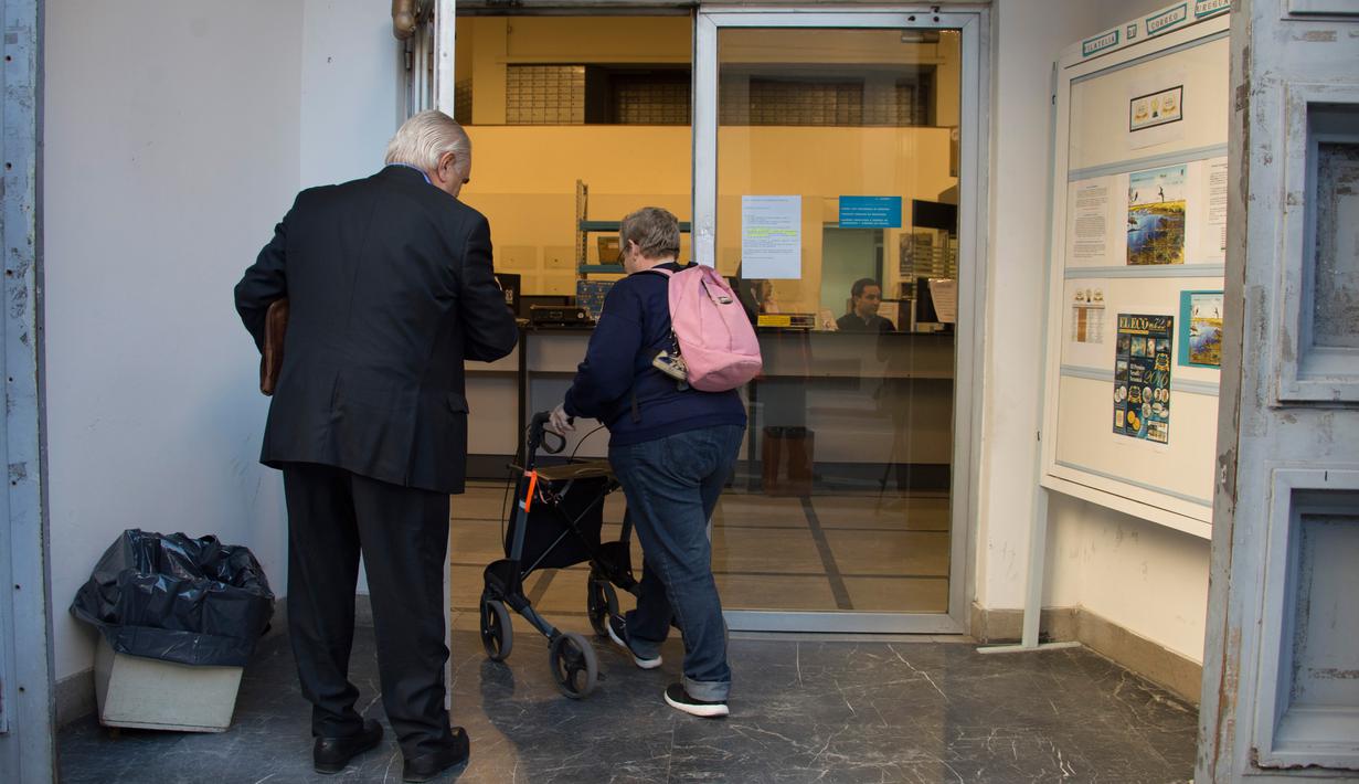 Beatriz (kanan) memasuki kantor pos untuk mendaftarkan diri sebagai konsumen ganja di Montevideo, Urugay, Selasa (2/5). Uruguay adalah negara pertama di dunia yang melegalkan ganja mulai dari proses produksi hingga penjualan. (Pablo PORCIUNCULA/AFP )