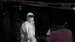 Petugas kesehatan mengenakan alat pelindung membantu pengunjung yang mengantre untuk mendapatkan tes virus corona di klinik skrining sementara virus corona di Seoul, Korea Selatan, Jumat (24/9/2021). (AP Photo/Lee Jin-man)