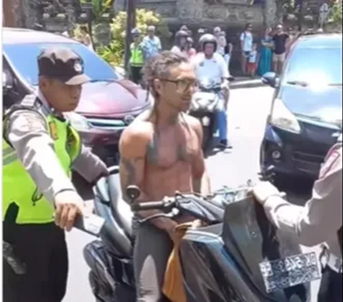 Sebuah video yang diunggah akun Instagram @lowslow.indonesia merekam saat seorang turis asing yang mengendarai motor dengan tak menggunakan helm dan telanjang dada mengamuk saat diberhentikan polisi.