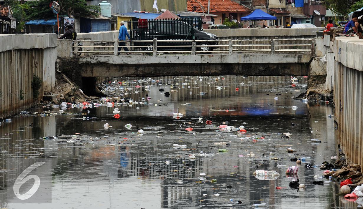 Warga melintasi jembatan kali di Jalan Petojo Utara VI, Jakarta, Senin (26/12). Kali tersebut terlihat kotor akibat ceceran sampah limbah plastik, botol minuman ringan dan sterefoam. (Liputan6.com/Helmi Fithriansyah)