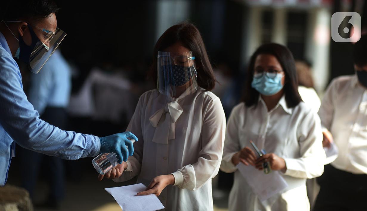 Petugas memberikan cairan hand sanitizer kepada peserta yang bersiap mengikuti Seleksi Kompetensi Bidang (SKB) berbasis Computer Assisted Test (CAT) untuk Calon Pegawai Negeri Sipil (CPNS) Kemenkumham di Gedung Kepegawaian Negara, Jakarta, Rabu (2/9/2020). (merdeka.com/Imam Buhori)