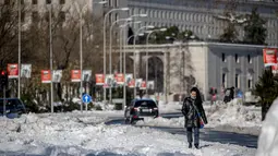 Seorang wanita berjalan di sepanjang Paseo Castellana yang tertutup salju di Madrid, Senin (11/1/2021). Ibu kota Spanyol itu berusaha bangkit kembali setelah menghadapi badai salju terburuk dalam 50 tahun terakhir yang melumpuhkan sebagian besar wilayah Spanyol tengah. (AP Photo/Manu Fernandez)