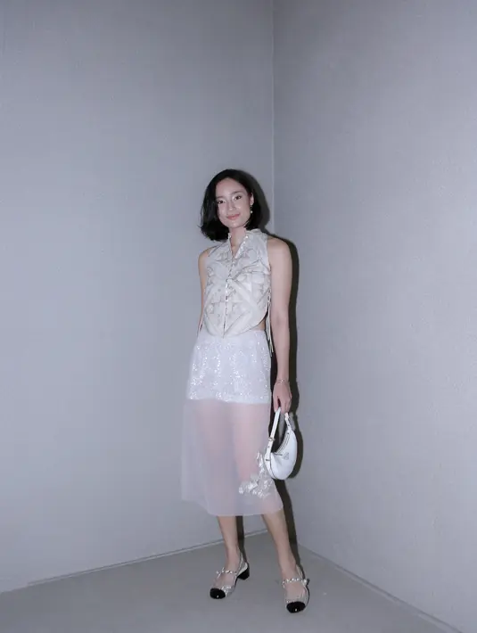 Tatjana Saphira menawan dalam balutan atasan tanpa lengan dengan aksen cheongsam yang manis, dipadu midi skirt dengan nuansa semi-transparan. Ia sempurnakan penampialnnya dengan mini handbag putih dan ballerina shoes. [Foto: Document/FIMELA]