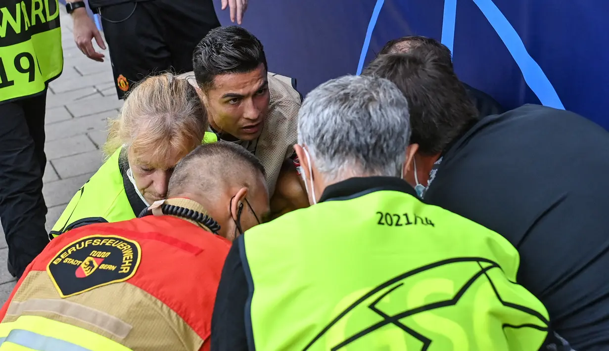 Cristiano Ronaldo menghampiri petugas lapangan yang terkena tendangan kerasnya saat sesi pemanasan jelang laga Liga Champions antara Young Boys vs Manchester United di Stadion Wankdorf, Rabu (14/9/2021). Bola sepakan Ronaldo mengenai petugas itu hingga terkapar. (Fabrice COFFRINI/AFP)
