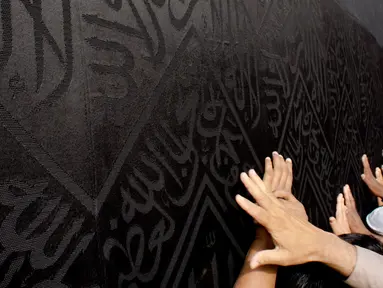 Umat muslim memanjatkan doa dengan menyentuh dinding Kabah selama menjalani ibadah umrah di Masjidil Haram, Mekkah, 4 Mei 2018. Banyak umat muslim yang menyambut bulan Ramadan dengan menjalankan ibadah umrah ke tanah suci. (AP Photo/Amr Nabil)