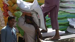 Seorang buruh Pakistan menurunkan karung beras di pasar grosir di Karachi (8/4). Kota ini terletak di Laut Arabia utara-barat Sungai Indus. Dengan populasi sekitar 14 juta, Karachi merupakan salah satu kota terpadat di dunia. (AFP Photo/Rizwan Tabassum)