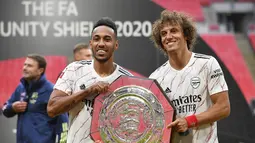 Penyerang Arsenal, Pierre-Emerick Aubameyang dan bek David Luiz berpose dengan trofi Community Shield usai pertandingan melawan Liverpool di stadion Wembley, London, Sabtu, (29/8/2020). Arsenal mengalahkan Liverpool 5-4 dalam adu penalti setelah pertandingan seri 1-1. (Justin Tallis/Pool via AP)