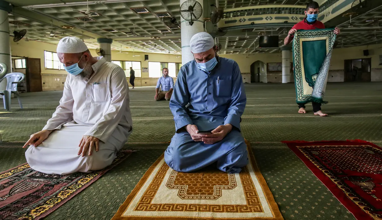 Para pria Palestina mengenakan masker saat ambil bagian dalam salat zuhur di masjid Al-Abrar di Rafah, selatan Jalur Gaza, Rabu (3/6/2020). Masjid-masjid kembali dibuka bagi jemaah menyusul pelonggaran pembatasan Covid-19 di Jalur Gaza. (Photo by SAID KHATIB / AFP)